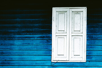 A blue wall with a white window. The window is open and the blue wall is painted