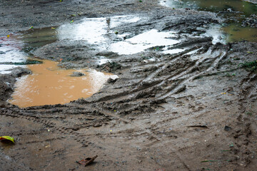 A muddy puddle with a person's shadow in it. The puddle is surrounded by mud and has a person's shadow in it
