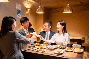 居酒屋で乾杯をする男女のビジネスパーソン