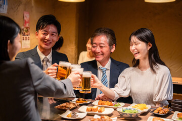 居酒屋で乾杯をする男女のビジネスパーソン