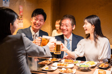 居酒屋で乾杯をする男女のビジネスパーソン