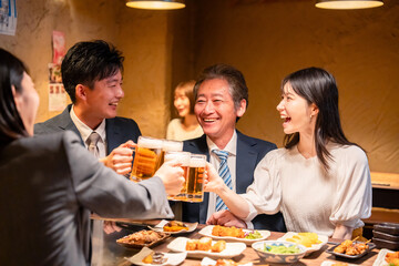 居酒屋で乾杯をする男女のビジネスパーソン