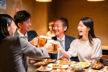 居酒屋で乾杯をする男女のビジネスパーソン
