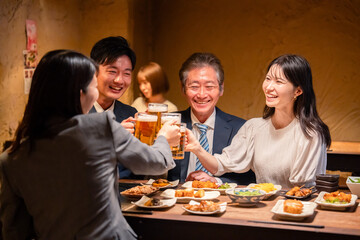 居酒屋で乾杯をする男女のビジネスパーソン