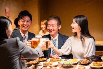 居酒屋で乾杯をする男女のビジネスパーソン
