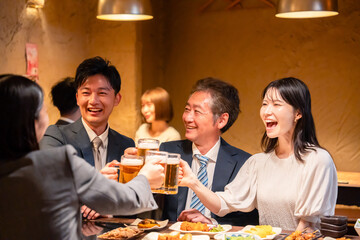 居酒屋で乾杯をする男女のビジネスパーソン