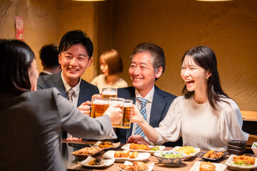居酒屋で乾杯をする男女のビジネスパーソン