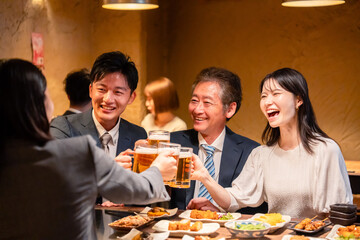 居酒屋で乾杯をする男女のビジネスパーソン