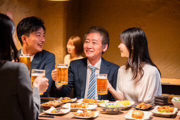 居酒屋で乾杯をする男女のビジネスパーソン