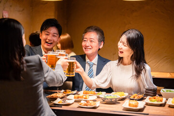 居酒屋で乾杯をする男女のビジネスパーソン