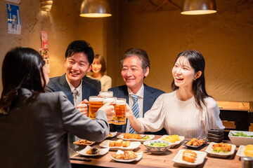 居酒屋で乾杯をする男女のビジネスパーソン