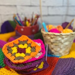 Crochet granny square motives set on the table, clews and hooks and basket cozy home photo