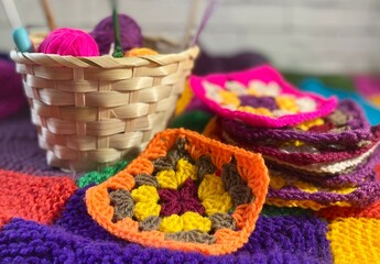 Crochet granny square motives set on the table, clews and hooks and basket cozy home photo