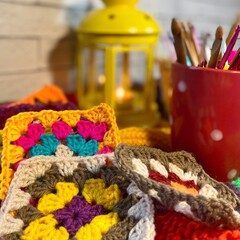 Crochet granny square motives set on the table, clews and hooks and basket cozy home photo