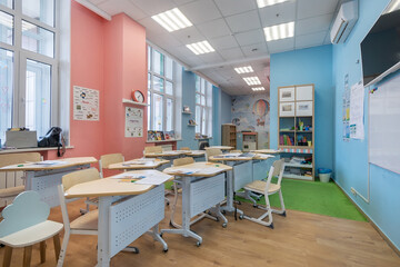 Specially equipped classroom with desks in kindergarten. The interior is decorated in pastel colors.