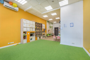 Colorful interior of a kindergarten room. A large shelf with toys and creative items.