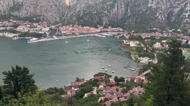 Static video from Franz Joseph stairs on Vrmac mountain, offering a scenic view of Kotor town, harbor, and boats on the calm water, October, panoramic perspective of the surrounding mountains
