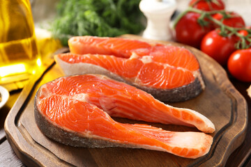 Board with fresh salmon steaks on table, closeup