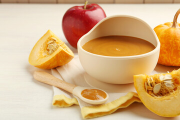 Delicious baby food in bowl and fresh ingredients on white wooden table