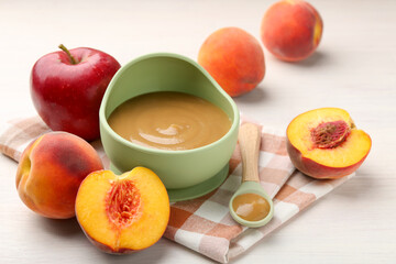Delicious baby food in bowl and fresh ingredients on white wooden table