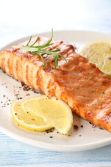 Delicious grilled salmon fillet served on light blue wooden table, closeup