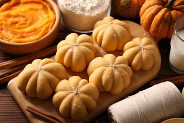Raw pumpkin shaped buns and ingredients on wooden table