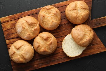 Homemade tasty buns on black textured table, top view