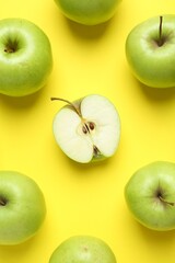 Flat lay composition with half of apple surrounded by ones on yellow background