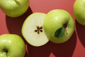 Whole and cut apples on red background, flat lay