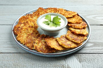 Delicious potato pancakes and sour cream on gray wooden table, closeup