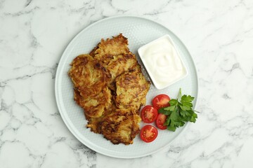 Delicious potato pancakes with fresh tomatoes, sour cream and parsley on white marble table, top view