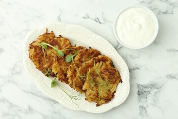 Delicious potato pancakes served on white marble table, flat lay