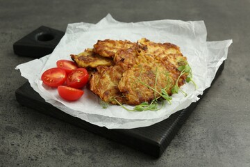Delicious potato pancakes with fresh tomatoes and microgreens on grey table, closeup