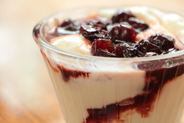 Close up the Yogurt in a glass bowl and cherry jam on top. Yoghurt dessert. Healthy sour-sweet dessert