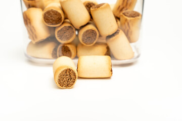Two filled cookies lie next to a glass container of dog biscuits. Dog treat.