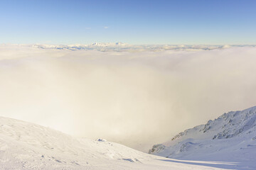 View from the snowy peak, with clouds in the valley, High Tatras in the background, sunny, winter, Slovakia, Chopok, wide angle lens