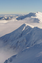 Cloud covered valley and snowy mountains from above, sunny, clear weather, winter, telephoto