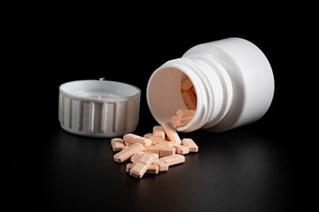 White bottle of sleeping pills opened with pills spilled out and isolated
