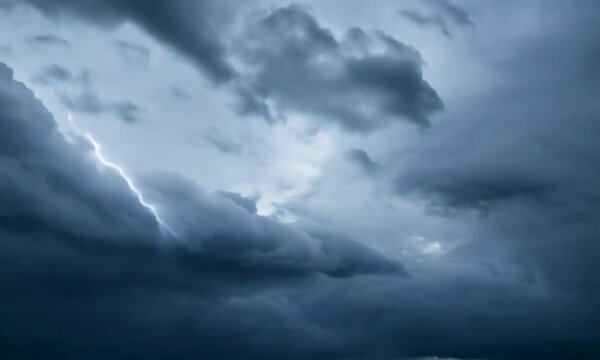 Close-up shot with moving storm: The camera starts by focusing on a swirling storm cloud, then pulls back to show the sky filling with dark, dramatic cloud formations and occasional lightning.