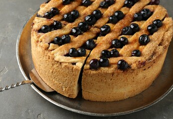 Taking slice of homemade blueberry pie on grey table, closeup