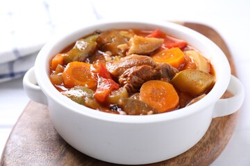 Delicious stew with vegetables in bowl on white table, closeup
