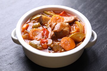 Delicious stew with vegetables in bowl on gray textured table, closeup