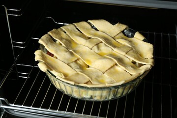 Baking dish with raw homemade apple pie in oven, closeup