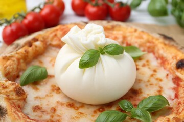 Delicious pizza with burrata cheese and basil on table, closeup