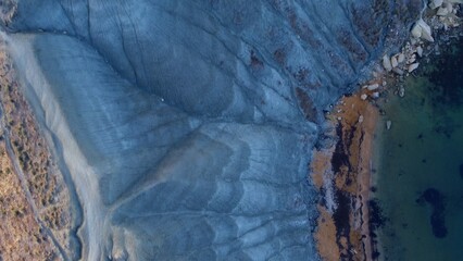 Clay cliffs flat rock cape Qarraba Bay, golden sand and emerald water in the early morning still in the shade. Aerial top down view. High quality photo