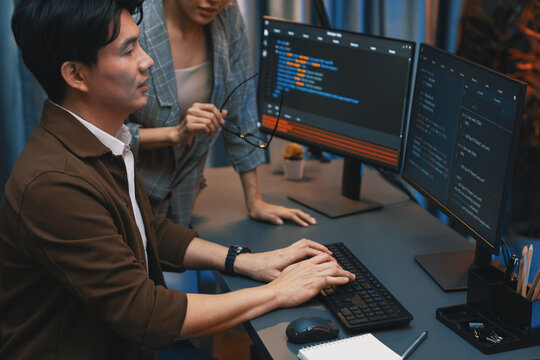 IT developers discussing with point to intelligent website development coder system running data online two screens information technology at neon light room at modern office. Infobahn.
