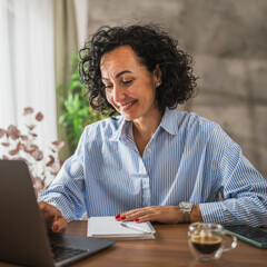Mature caucasian woman work or learn use notebook and laptop from home