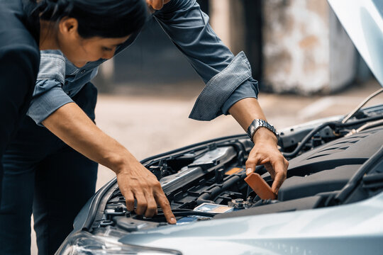 Man help woman fix the car problem. He pop up the car hood to repair the damaged part. uds