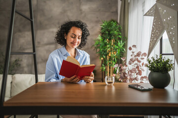Beautiful mature woman sit at modern living room and read a book