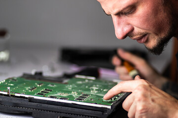 A man works intently on a board, using a brush to clean it. He carefully inspects the parts while...